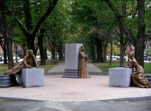 Sculptures of poets framed by tall trees