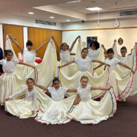 Young dancers in flowing skirts pose in a group