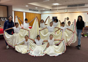 Young dancers in flowing skirts pose in a group