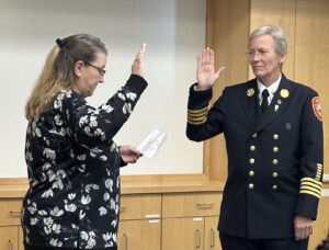 A town clerk and a uniformed fire chief with right hands raised as the new chief is sworn in.