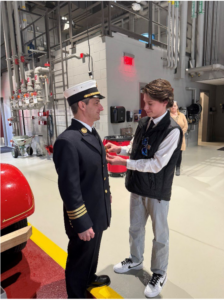 Deputy Chief Sammet in a fire station is pinned by his son, Jordan