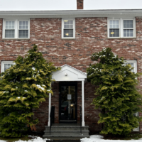 A Dover Heights building entrance framed by evergreen trees.