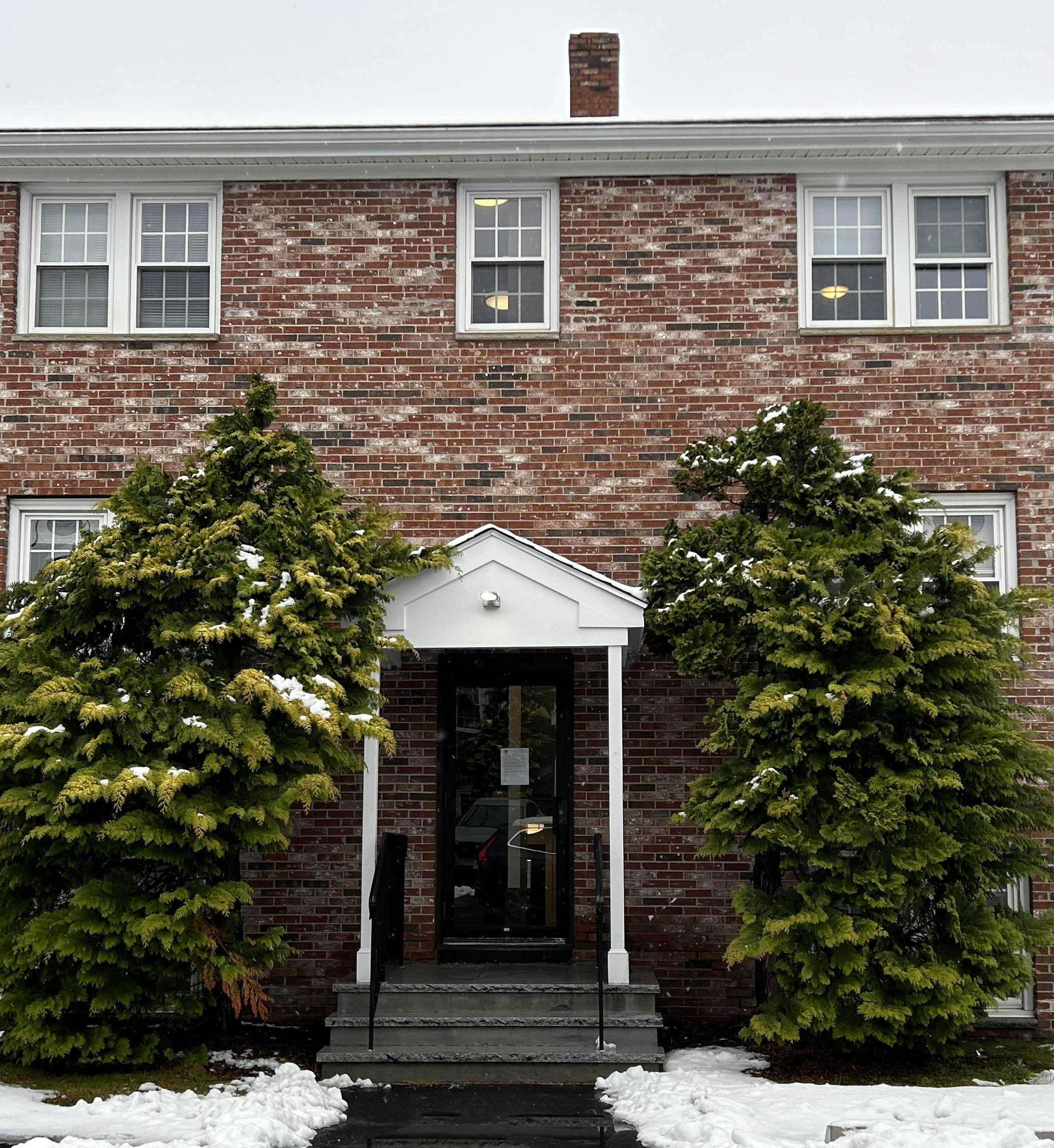 A Dover Heights building entrance framed by evergreen trees.