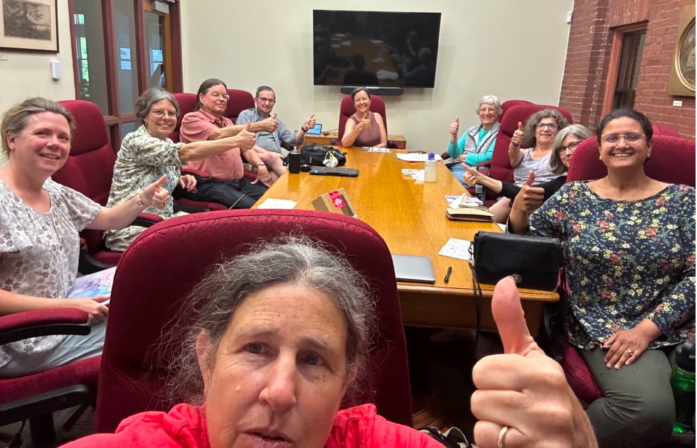 Ten people around a conference table all with thumbs up indicating consensus